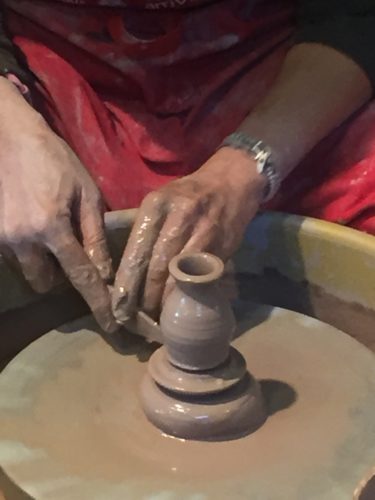 Close up of someone throwing a pot on the wheel